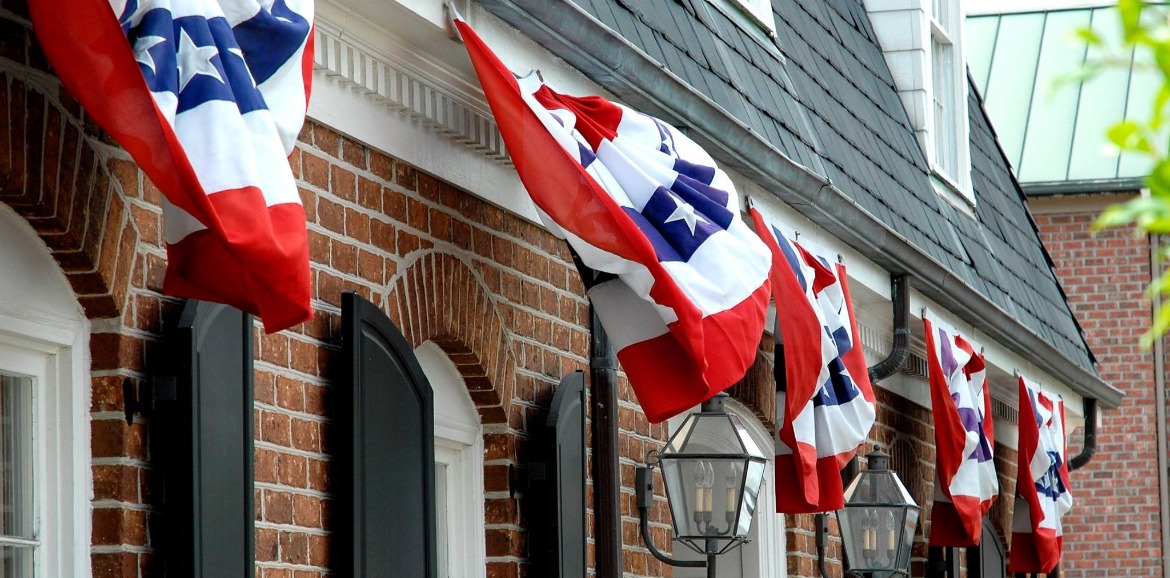 4th of July Flags above windows on a street in Southport | Better Beach Rentals